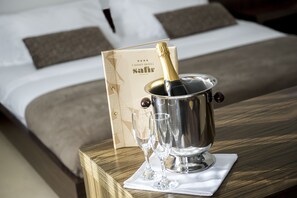 En säng med ett huvudgavel av trä, ett sängbord med en champagnekylare, glas och ett kort.