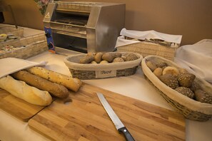 A kitchen area with a bread basket, a cutting board, a knife, and a bread oven. - Hotel Safir Casino (Sezana)