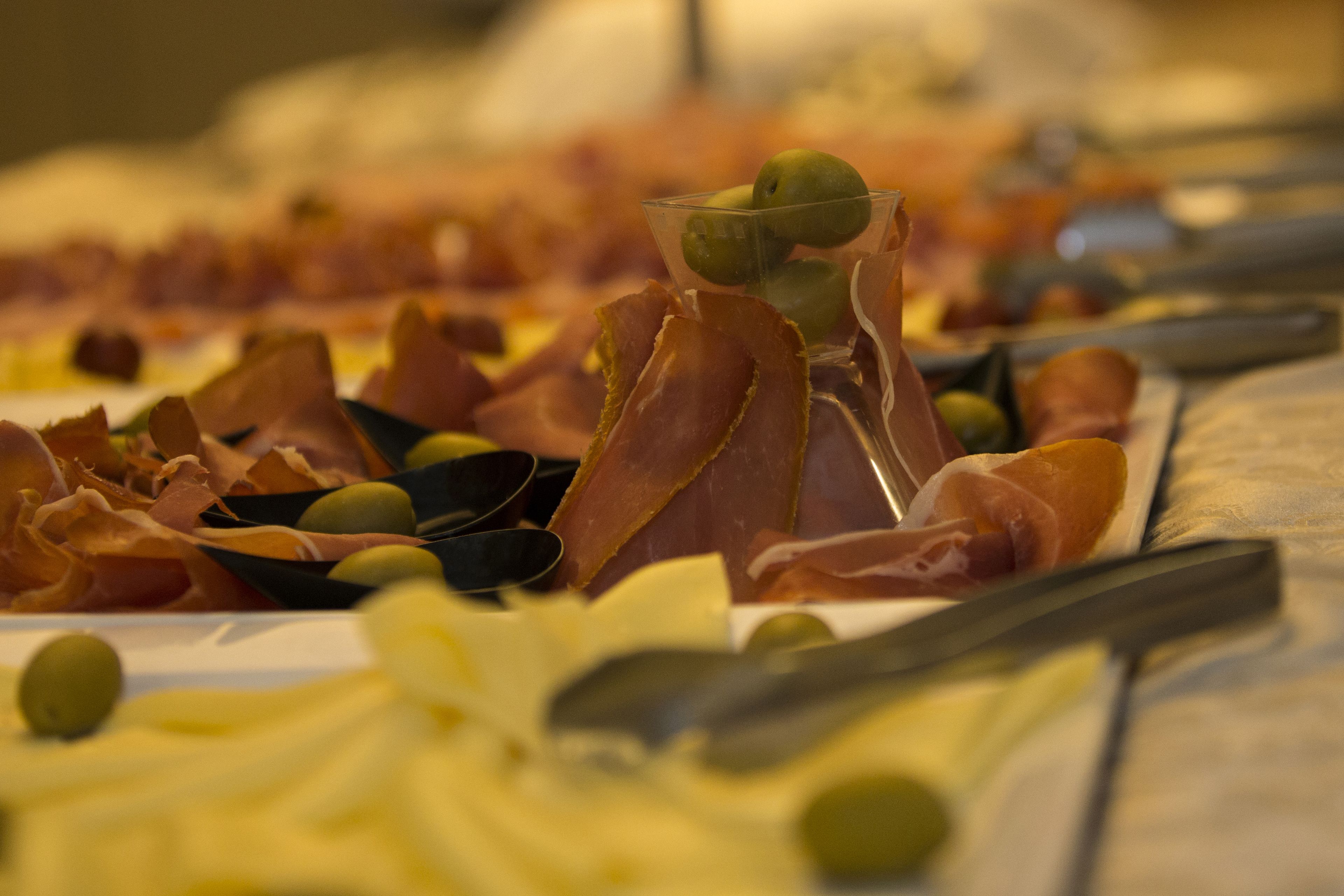 A buffet with various meats, cheeses, and olives.