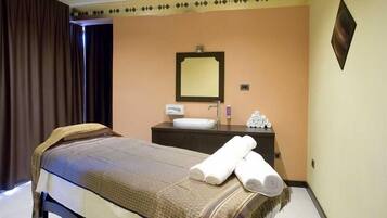 Una habitación de hotel con cama, mesita de noche, espejo, lavamanos y toallero.