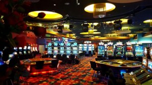 Een casino met verschillende speelautomaten, een kleurrijk tapijt en verlichting.