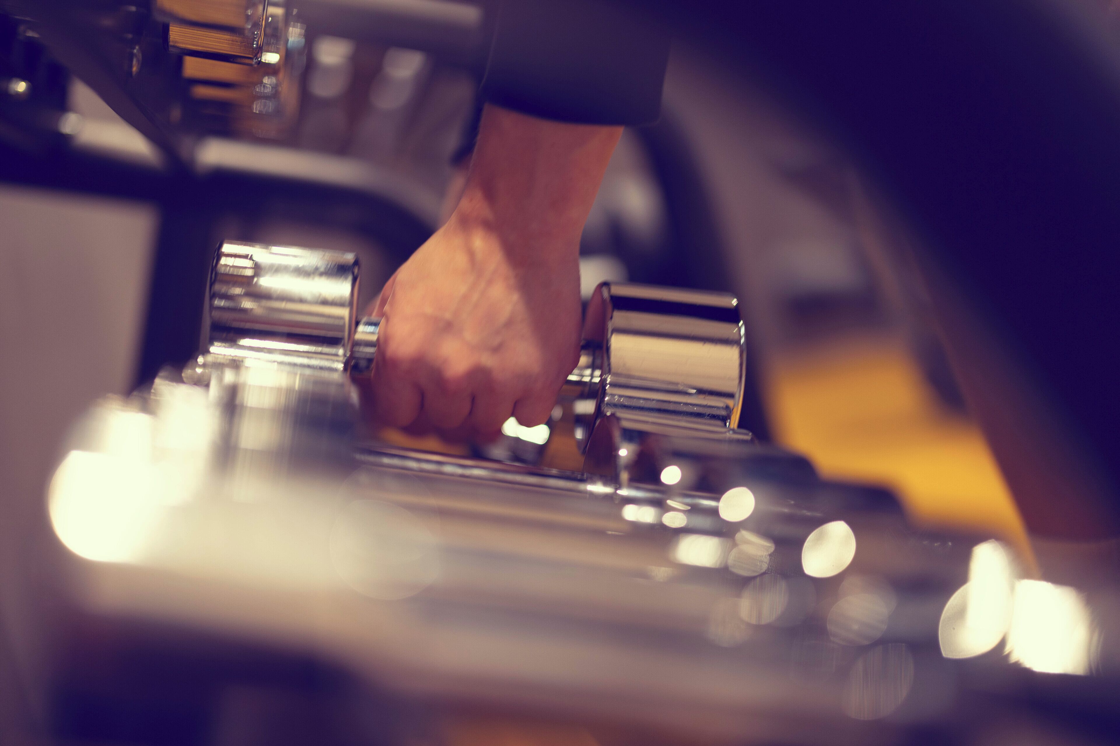 A close-up of a hand gripping a metallic object, likely a part of machinery or equipment.