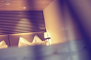 Quarto de hotel com cama, cabeceira e janela com persianas.