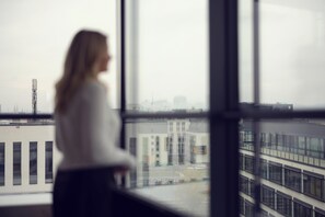A person standing by a window with a view of a building complex. - roomz Vienna Prater (Vienna)