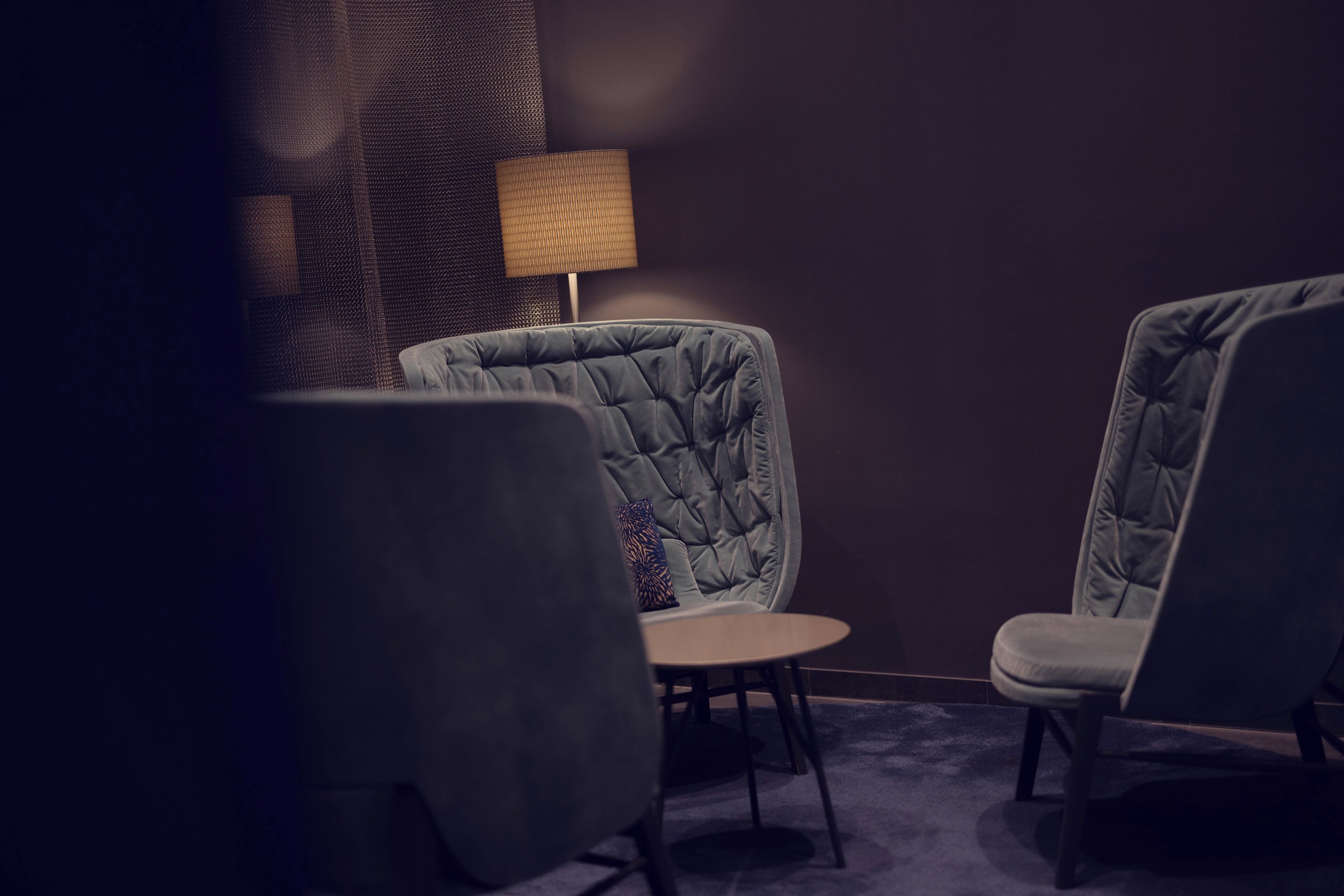 A room with two upholstered chairs, a small round table, and a lamp.