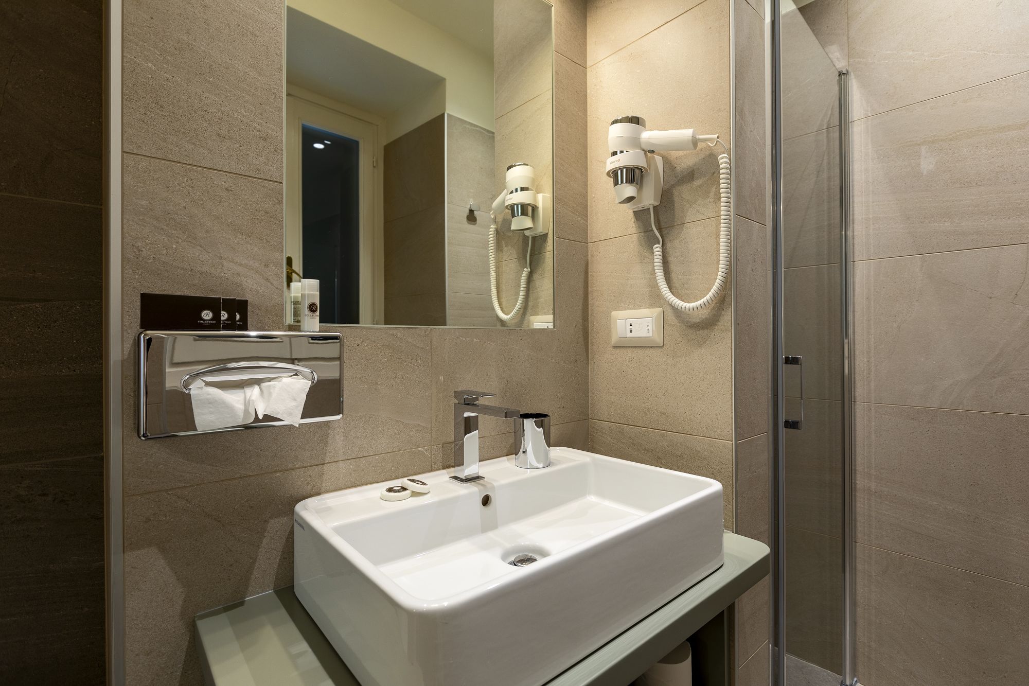 A modern bathroom with a large mirror, a sink, and a shower.