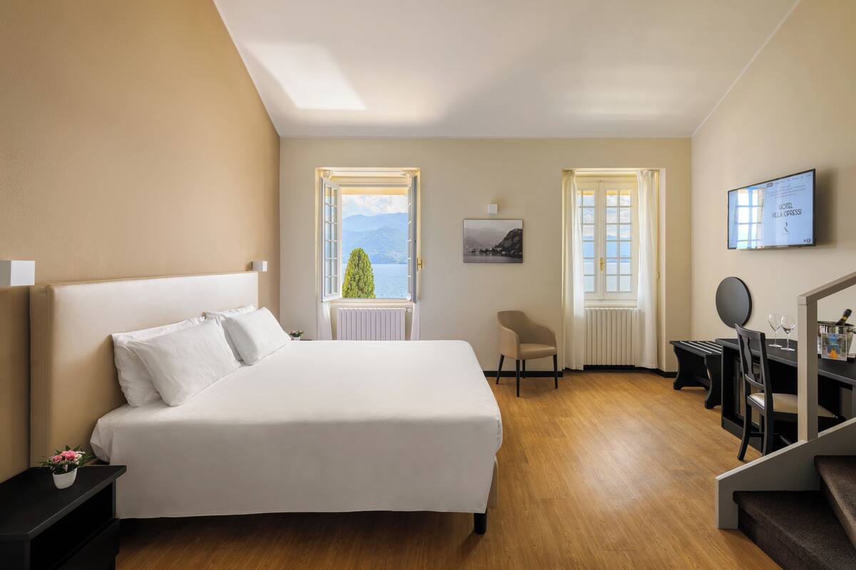 A hotel room with a bed, a desk, a chair, and a TV.