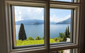 A view through a window of a lake with mountains in the background. - Hotel Villa Cipressi - by R Collection Hotels (Varenna)
