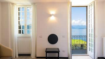 Una habitación con vistas a un lago y montañas, una lámpara redonda montada en la pared, una mesa negra y un radiador.