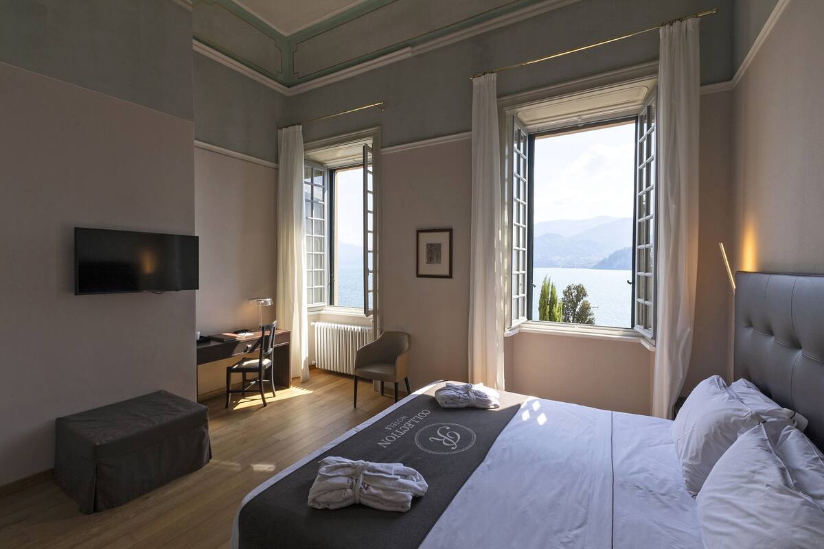 A hotel room with a bed, a desk, a chair, and a TV.