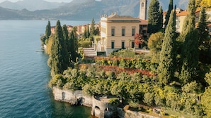 Una propiedad junto al lago con un edificio destacado, un sendero de piedra y vistas al lago y las montañas.