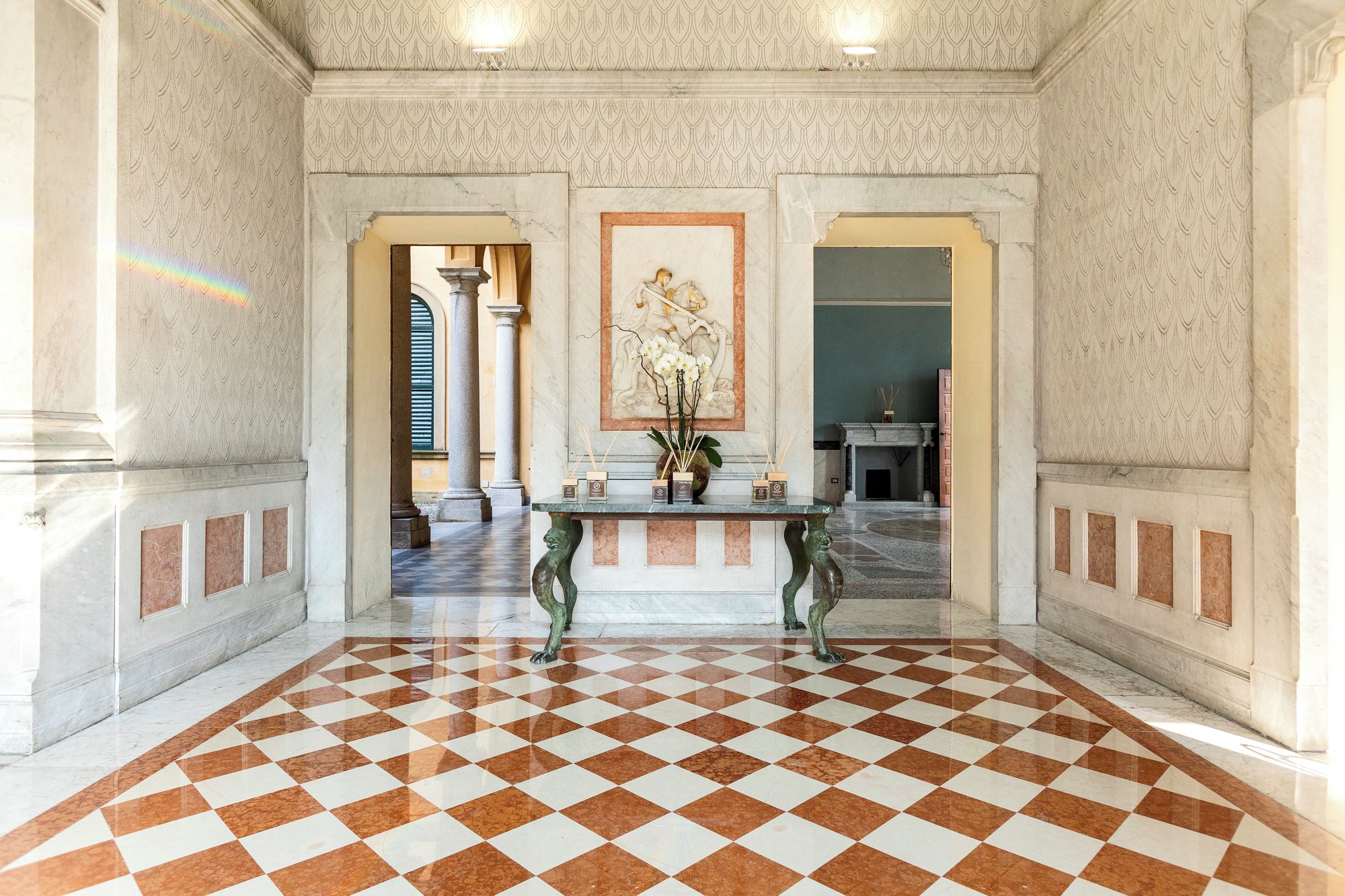Un hall d’entrée spacieux, doté d’un sol à carreaux, de murs en marbre et d’une table centrale agrémentée d’objets décoratifs.