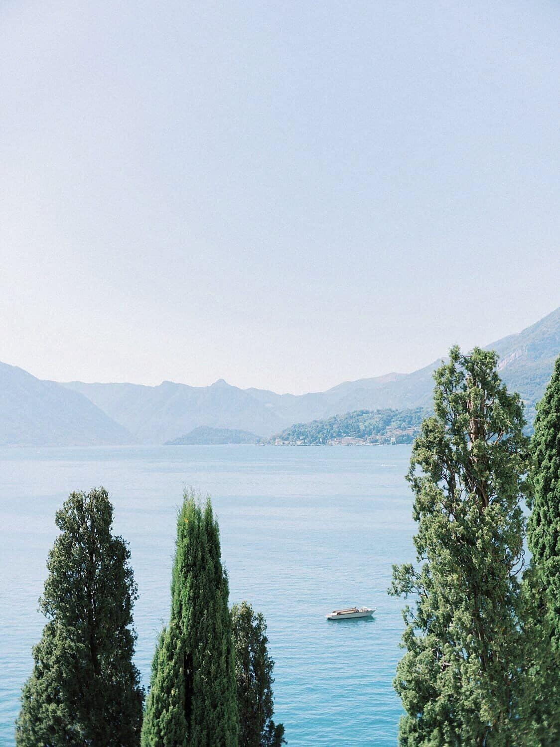 A calm lake with a boat, surrounded by mountains and trees.