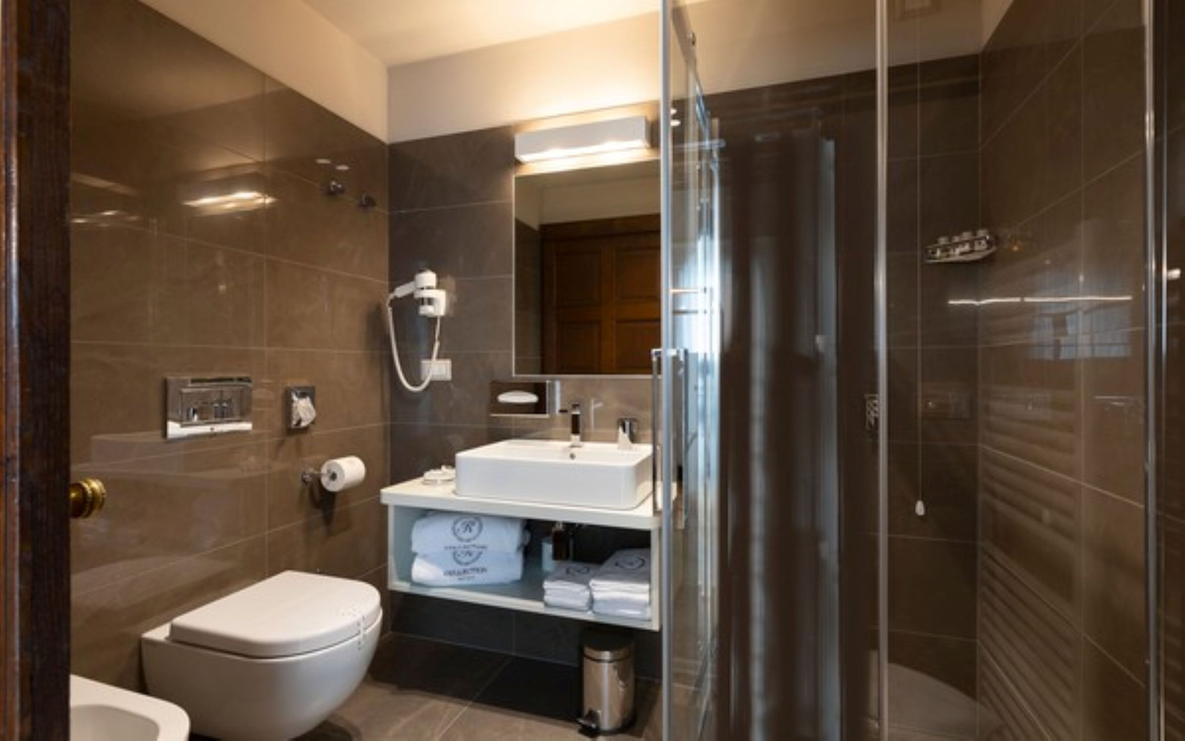 Un baño moderno con inodoro, lavamanos y zona de ducha.