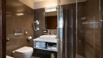 Un baño moderno con inodoro, lavamanos y zona de ducha.