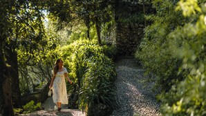 A pathway surrounded by lush greenery and a stone wall. - Hotel Villa Cipressi - by R Collection Hotels (Varenna)