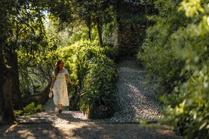 A pathway surrounded by lush greenery and a stone wall. - Hotel Villa Cipressi - by R Collection Hotels (Varenna)