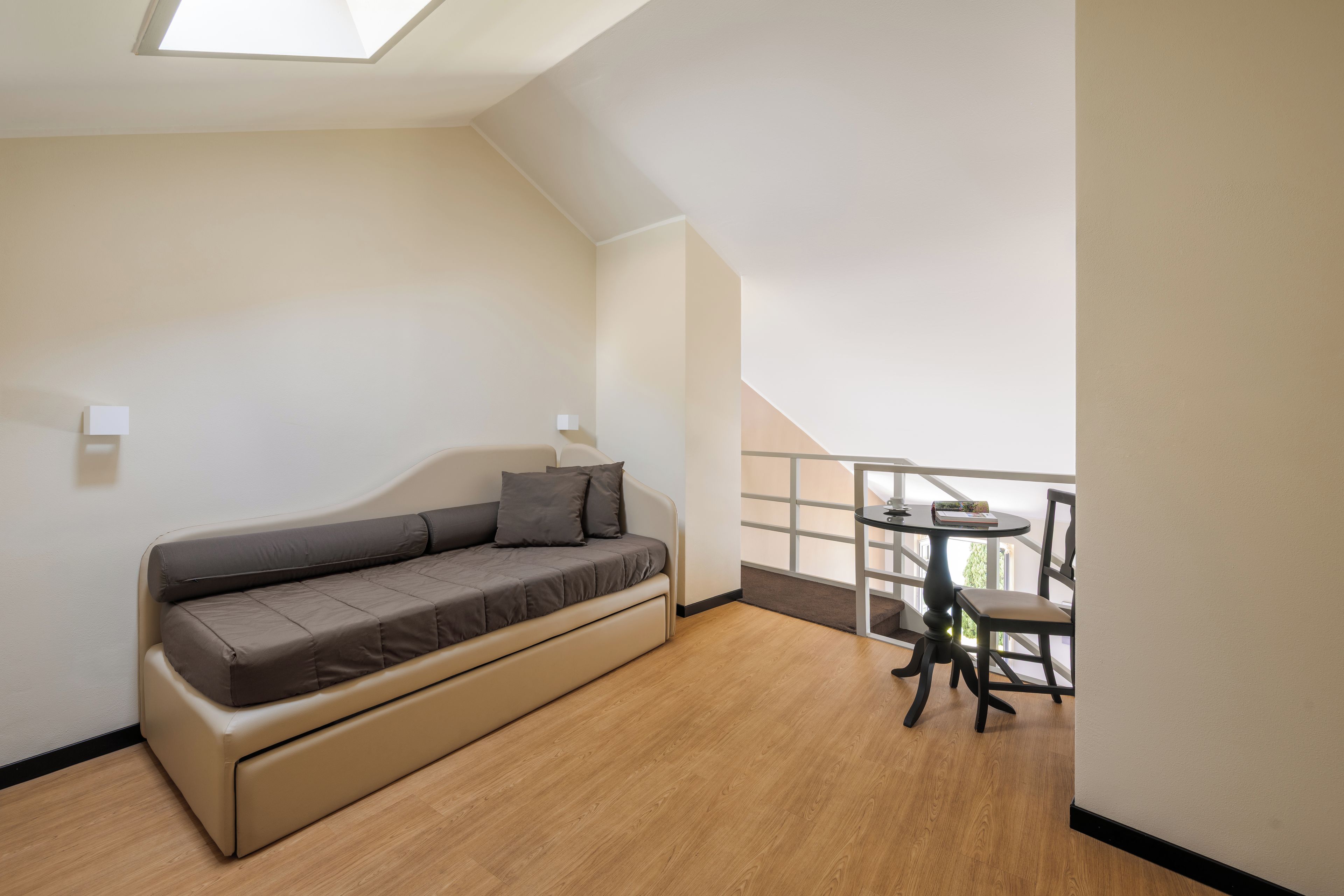 Ein modernes Wohnzimmer mit einer Couch, einem kleinen Tisch und einem Balkon mit Geländer.
