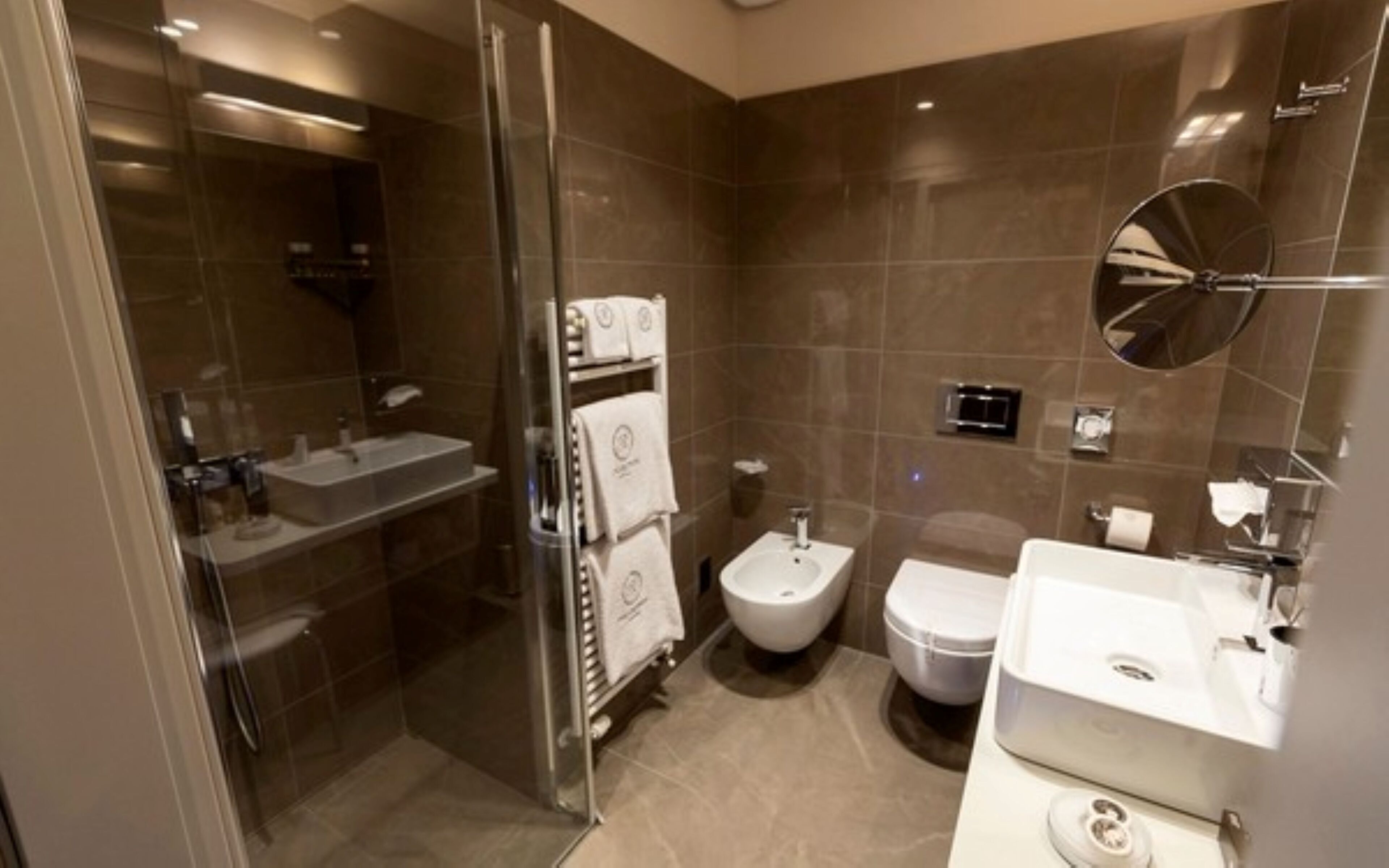 Un baño moderno con cabina de ducha de vidrio, un bidé, un inodoro y un lavabo.