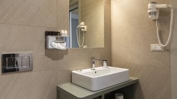 A bathroom with a white sink, a mirror, a hairdryer, and a towel rack.