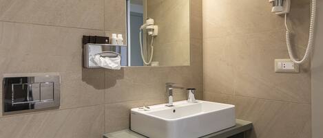 A bathroom with a white sink, a mirror, a hairdryer, and a towel rack.