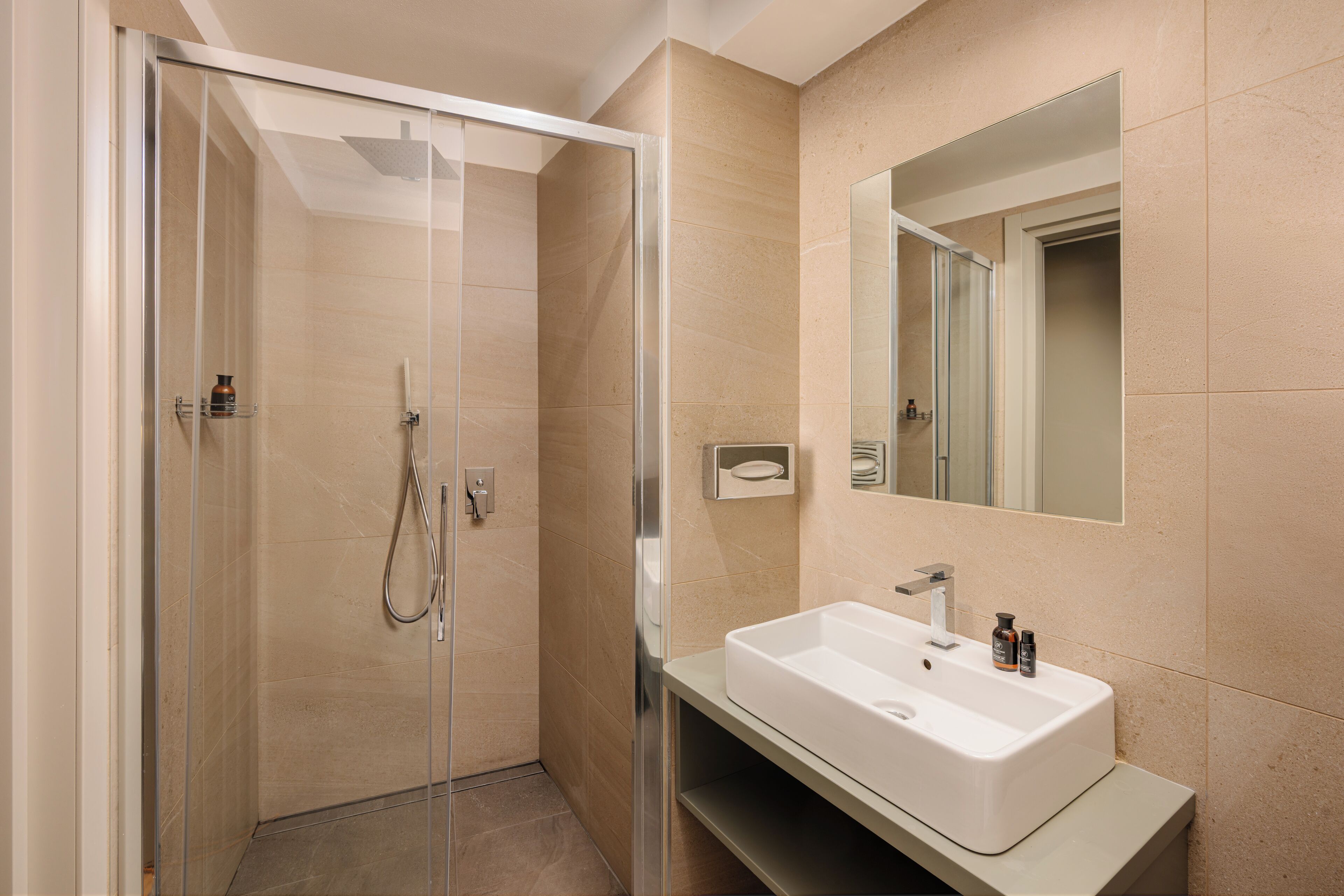 A modern bathroom with a glass-enclosed shower, a white sink, and a large mirror.