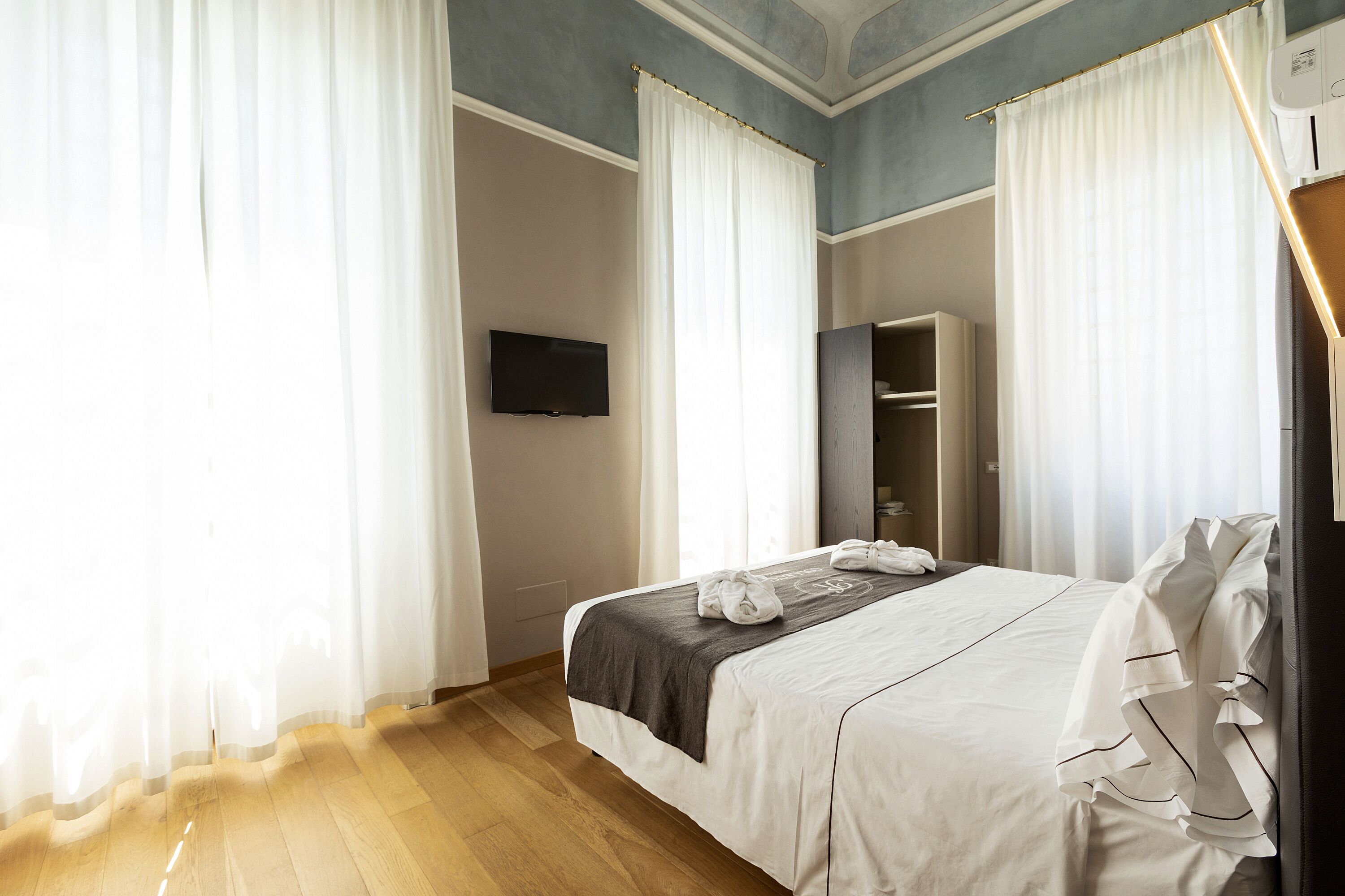 A hotel room with a bed, a television, and a wardrobe.