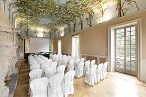 A spacious hall with rows of white chairs, a large screen, and a view of greenery through the windows. - Hotel Villa Cipressi - by R Collection Hotels (Varenna)
