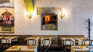 Un interior de restaurante con mesas dispuestas para comer, menús colgados en la pared y luminarias fijadas a la pared.