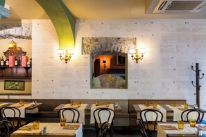 Un interior de restaurante con mesas dispuestas para comer, menús colgados en la pared y luminarias fijadas a la pared.