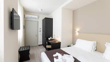 A hotel room with a bed, a desk, a chair, a TV, and a wardrobe.