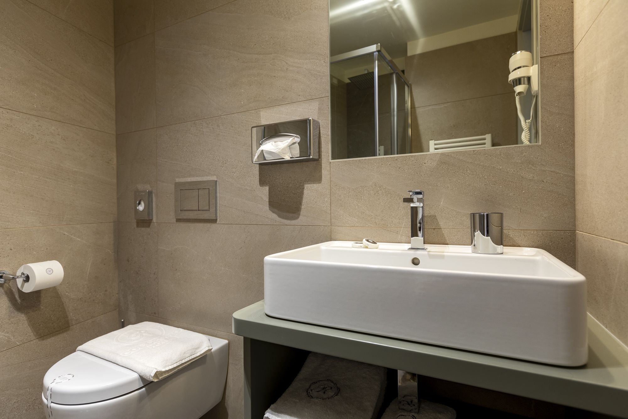 A bathroom with a white sink, a mirror, a towel, and a toilet.