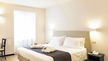 A hotel room with a bed, bedside tables, a chair, and a window with curtains.