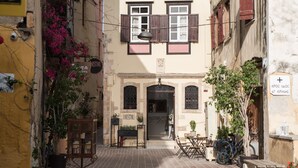Una calle estrecha con un café llamado "HARISTAR" al final. Hay plantas en macetas y una bicicleta estacionada afuera.