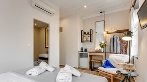 Una habitación de hotel con cama, escritorio, silla, una mesita con lámpara y espejo.