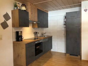 Eine moderne Küche mit dunklen Schränken, einer Holzarbeitsplatte, einer Kaffeemaschine und einem Spülbecken.