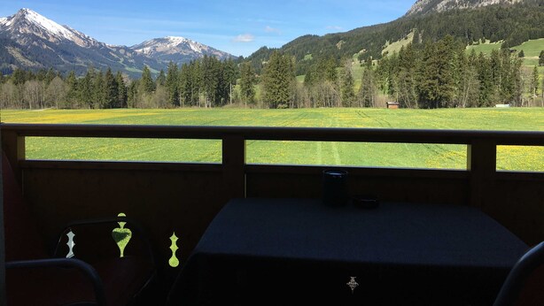 Une pièce avec vue sur un paysage montagneux, une fenêtre et une petite table avec une tasse.