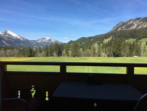Une pièce avec vue sur un paysage montagneux, une fenêtre et une petite table avec une tasse.