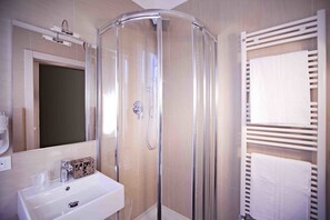 Bathroom features a glass-enclosed shower, handheld showerhead, and wall-mounted faucet.