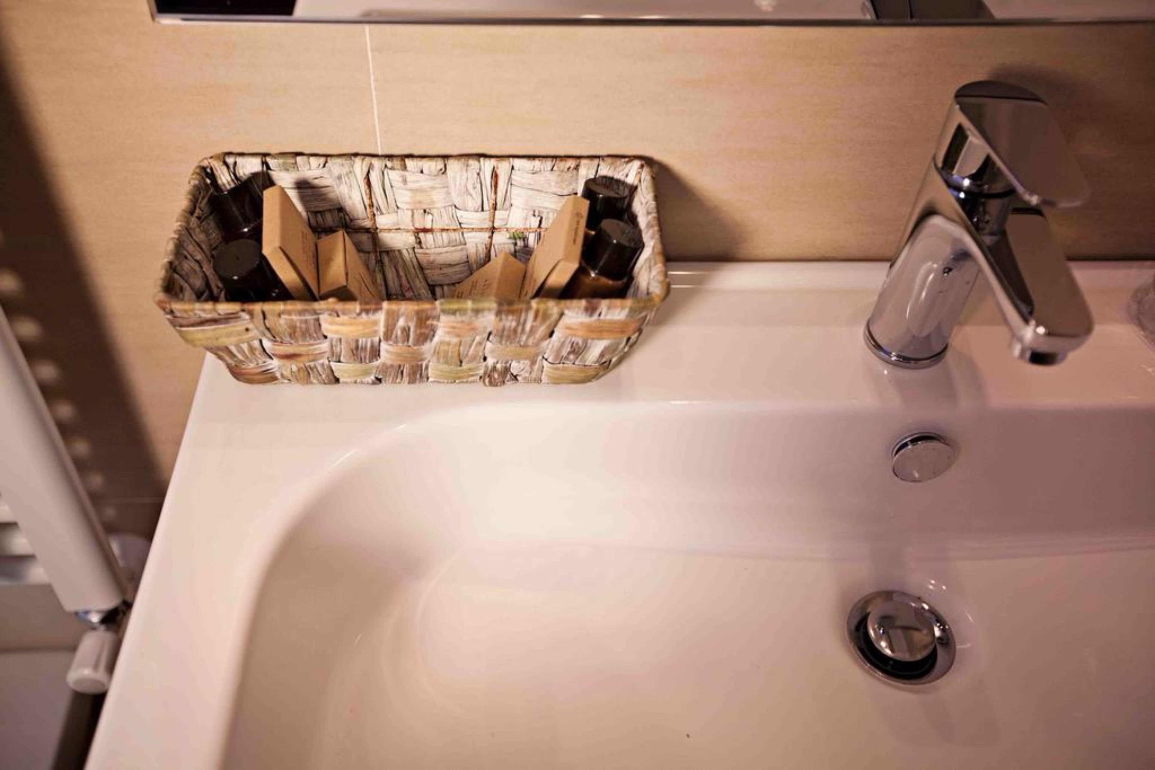 A bathroom sink with a clear glass soap dish containing toiletries.
