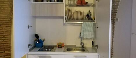 A compact kitchen with white cabinets, a built-in sink, and a small countertop.