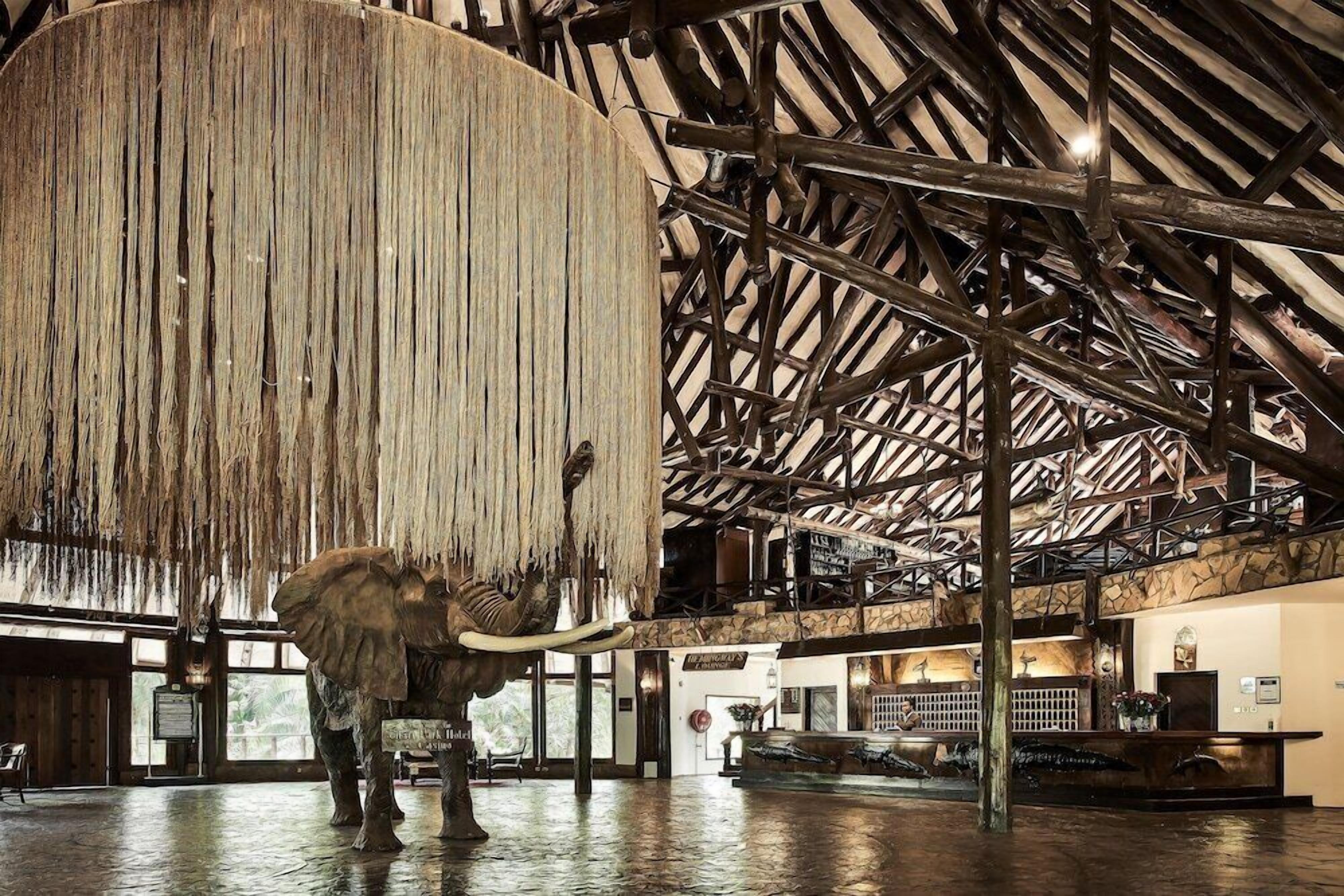 A reception area with a large elephant sculpture, wooden beams, and a stone wall.