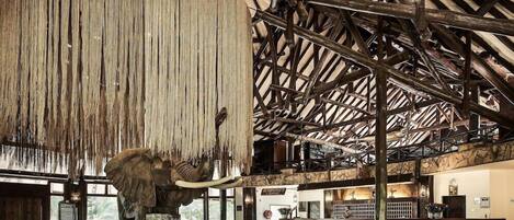 A reception area with a large elephant sculpture, wooden beams, and a stone wall.