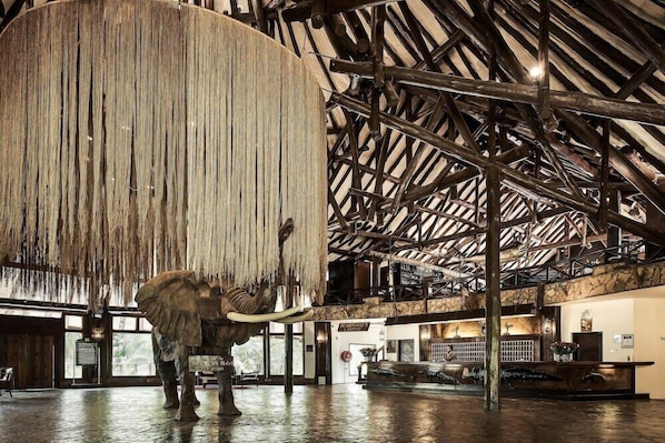 A reception area with a large elephant sculpture, wooden beams, and a stone wall.