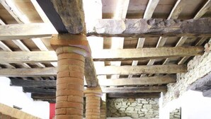 A corridor with exposed wooden beams and brick columns, leading to a door with a coat rack. - LeAmorine White House B&B (Predappio)