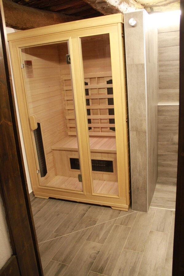A sauna room with wooden benches and a glass door. - LeAmorine White House B&B (Predappio)
