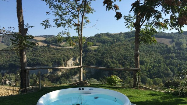 A hot tub in a garden with a view of a forested valley. - LeAmorine White House B&B (Predappio)