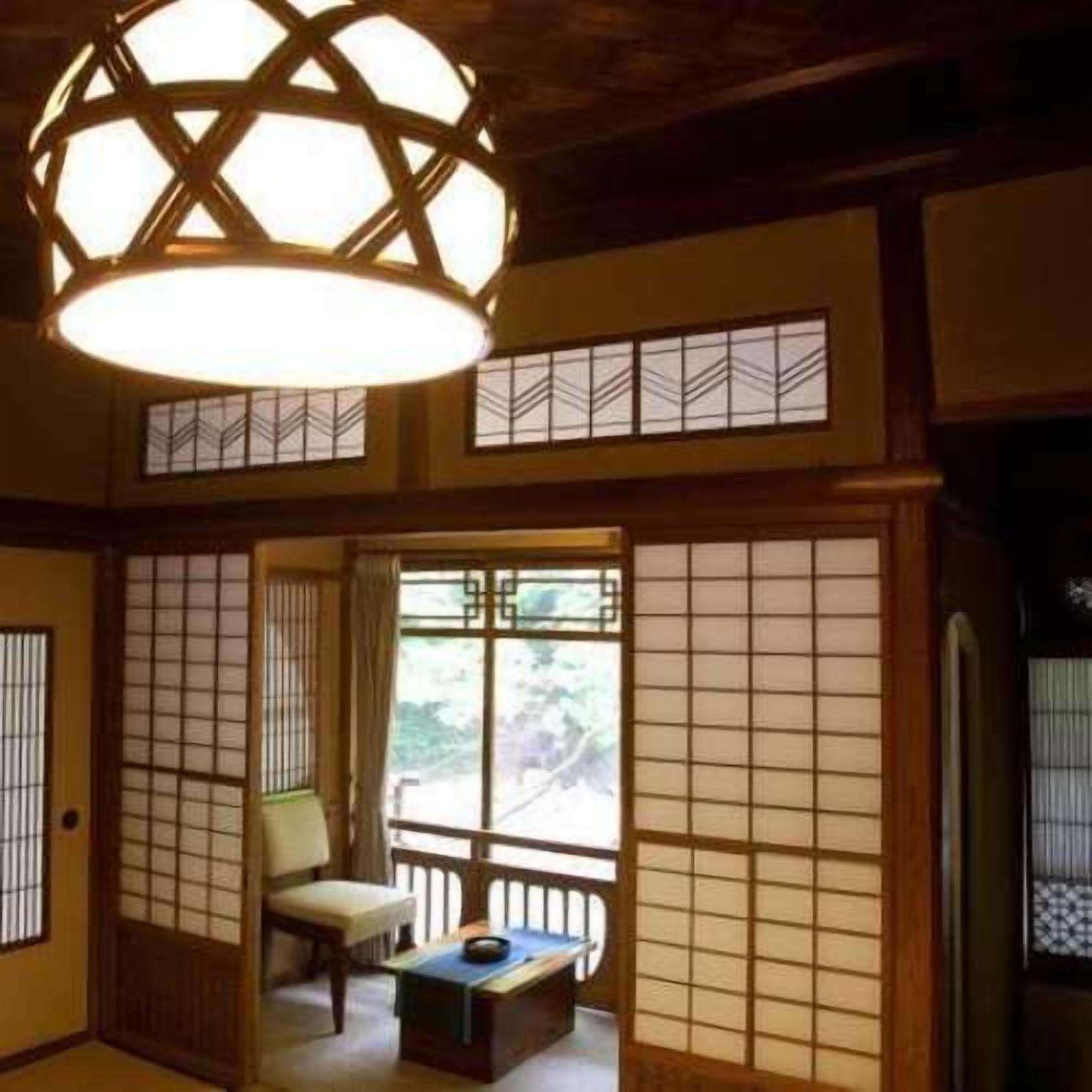 Una habitació japonesa tradicional amb tatami, una taula baixa amb coixí, portes corredisses i una làmpada al sostre.