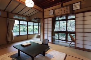 A traditional Japanese room with tatami flooring, a low table, and sliding doors. - Fukuzumiro (Hakone)