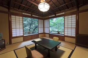 A traditional Japanese room with tatami flooring, a low table, and sliding doors with a view of trees. - Fukuzumiro (Hakone)